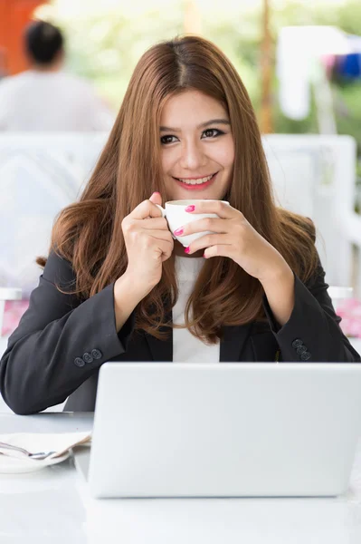 Asia joven mujer de negocios sentado en la cafetería con ordenador portátil y café — Foto de Stock