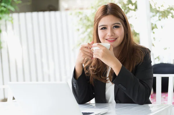 Asia joven mujer de negocios sentado en la cafetería con ordenador portátil y café —  Fotos de Stock