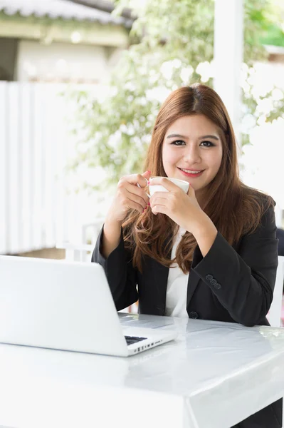 Asia joven mujer de negocios sentado en la cafetería con ordenador portátil y café — Foto de Stock