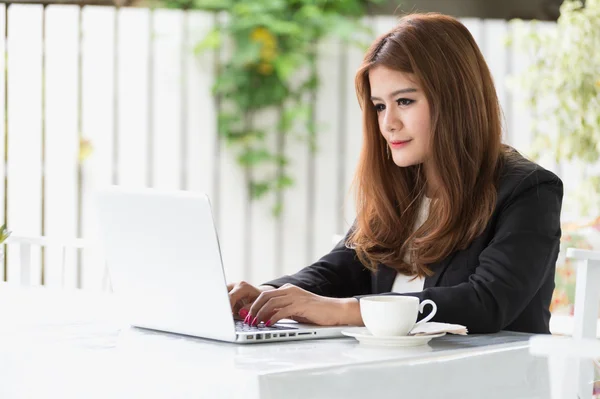 Asia joven mujer de negocios sentado en la cafetería con ordenador portátil y café — Foto de Stock