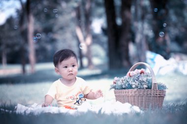 Sabun köpüğü ile yeşil çimenlerin üzerinde oturan erkek Asya bebek 