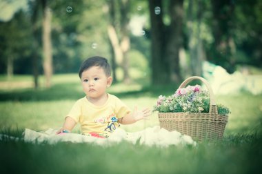 Sabun köpüğü ile yeşil çimenlerin üzerinde oturan erkek Asya bebek 