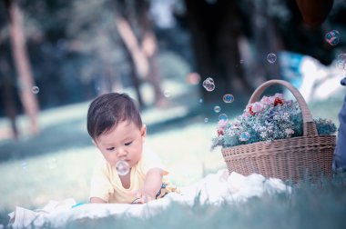 Sabun köpüğü ile yeşil çimenlerin üzerinde oturan erkek Asya bebek 