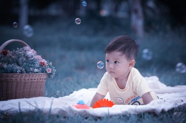 Sabun köpüğü ile yeşil çimenlerin üzerinde oturan erkek Asya bebek 