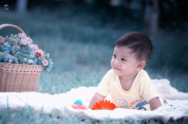 Sabun köpüğü ile yeşil çimenlerin üzerinde oturan erkek Asya bebek 