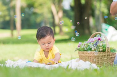 Sabun köpüğü ile yeşil çimenlerin üzerinde oturan erkek Asya bebek 