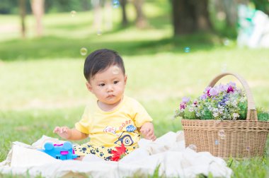 Sabun köpüğü ile yeşil çimenlerin üzerinde oturan erkek Asya bebek 