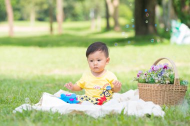 Sabun köpüğü ile yeşil çimenlerin üzerinde oturan erkek Asya bebek 
