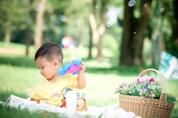 Sabun köpüğü ile yeşil çimenlerin üzerinde oturan erkek Asya bebek 