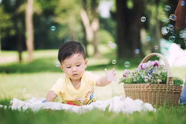 Asia Baby boy sitting on green grass with soap bubbles — Stock Photo, Image