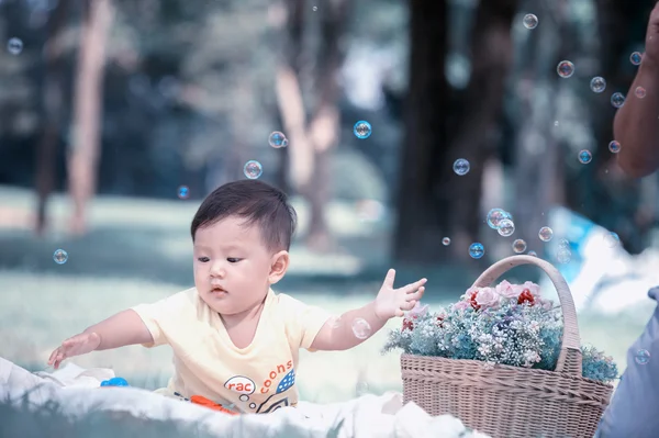 Azië jongetje zittend op groen gras met zeepbellen — Stockfoto
