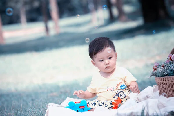 Asia Baby boy sitting on green grass with soap bubbles — Stock Photo, Image