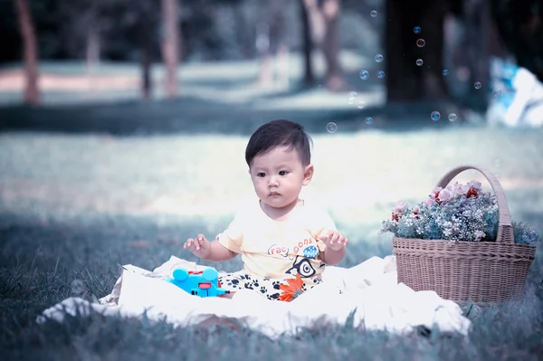 เอเชีย เด็กชายนั่งบนหญ้าสีเขียวกับฟองสบู่ — ภาพถ่ายสต็อก