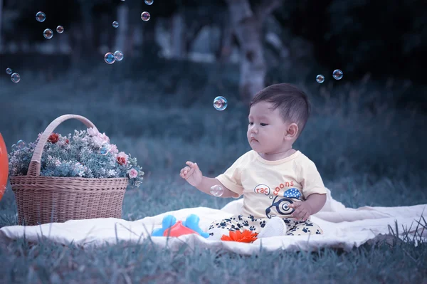 Asia Baby boy sitting on green grass with soap bubbles — Stock Photo, Image