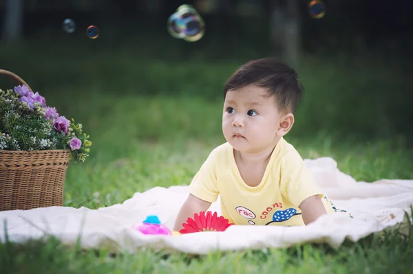 Asia Niño sentado sobre hierba verde con burbujas de jabón — Foto de Stock