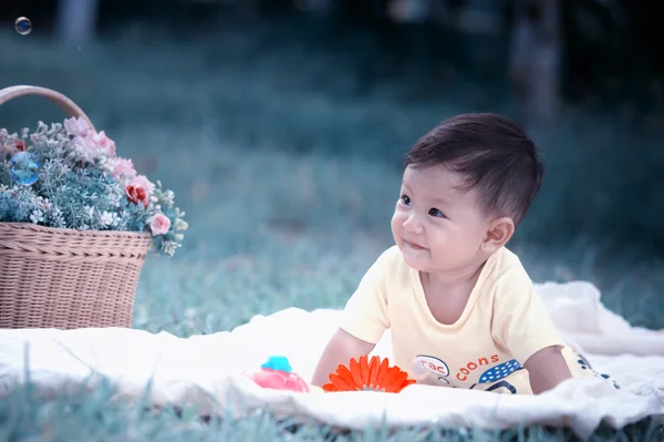 Sabun köpüğü ile yeşil çimenlerin üzerinde oturan erkek Asya bebek 