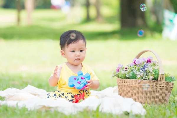 Asia Niño sentado sobre hierba verde con burbujas de jabón — Foto de Stock