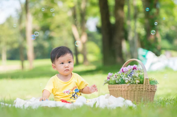 Asia Niño sentado sobre hierba verde con burbujas de jabón — Foto de Stock