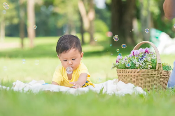 Азія хлопчика, сидячи на зеленій траві з мильними бульбашками — стокове фото