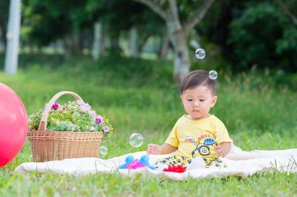 Asia Baby boy sitting on green grass with soap bubbles — Stock Photo, Image