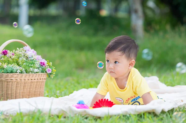 เอเชีย เด็กชายนั่งบนหญ้าสีเขียวกับฟองสบู่ — ภาพถ่ายสต็อก