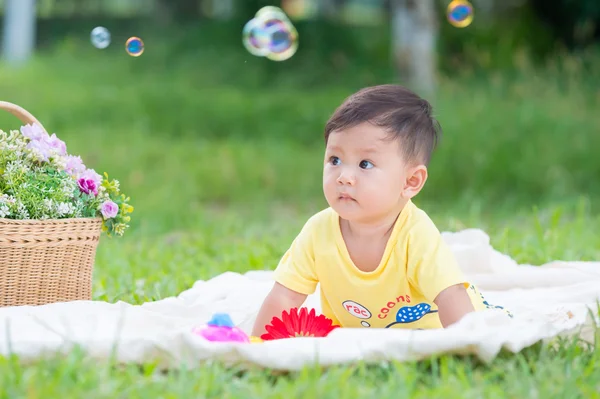 Sabun köpüğü ile yeşil çimenlerin üzerinde oturan erkek Asya bebek 