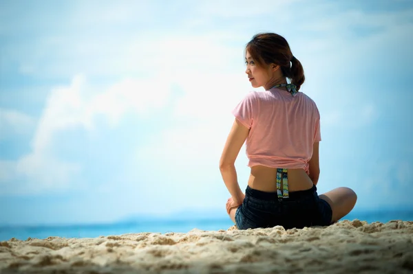 Asia fiatal nő ül a strandon — Stock Fotó