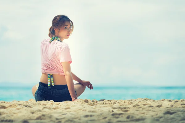 Asia fiatal nő ül a strandon — Stock Fotó