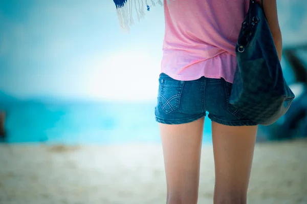 Молодая модная женщина в джинсовых шортах позирует на пляже — стоковое фото