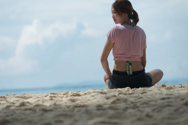Азиатская молодая женщина сидит на пляже — стоковое фото