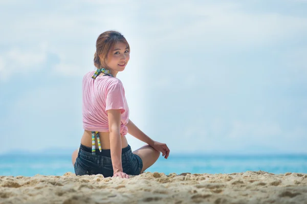 Азиатская молодая женщина сидит на пляже — стоковое фото