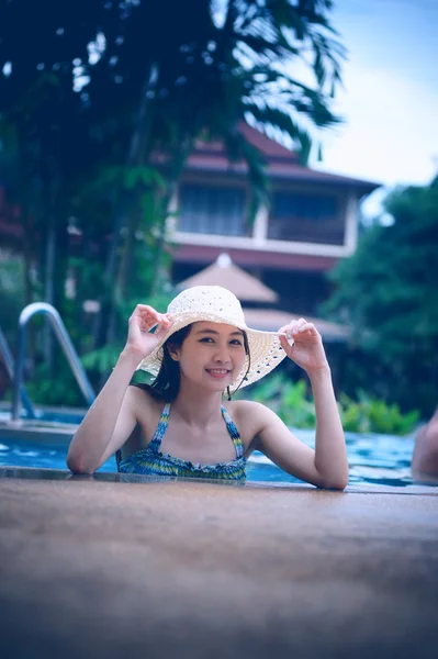 Ásia mulher bonita em chapéu desfrutando de piscina — Fotografia de Stock