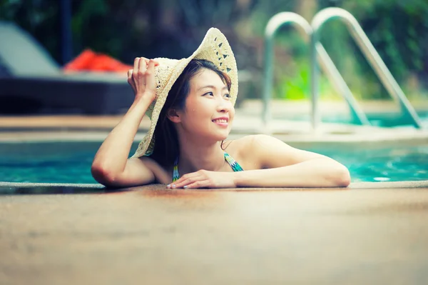 Asia hermosa mujer y gran sombrero relajante en la piscina — Foto de Stock