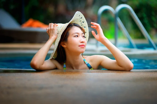 Ásia mulher bonita em chapéu desfrutando de piscina — Fotografia de Stock