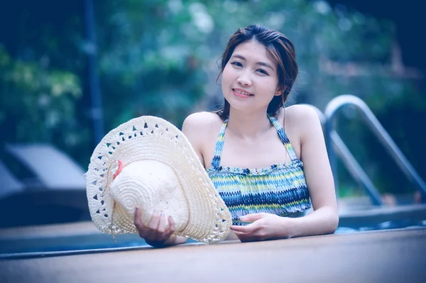Ásia mulher bonita e grande chapéu relaxante na piscina — Fotografia de Stock