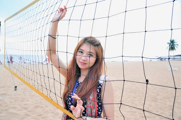 Asiatisch junge frau hinter volleyballnetz am strand, sport conce — Stockfoto