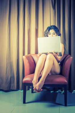 Asya güzel bikini kadın sandalyede, vintage tarzı dizüstü bilgisayar ile