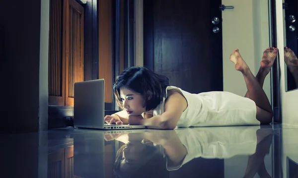 Asia office woman lying on floor with laptop at home