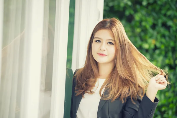 Ásia confiante jovem empresária em terno de mãos dadas no cabelo — Fotografia de Stock