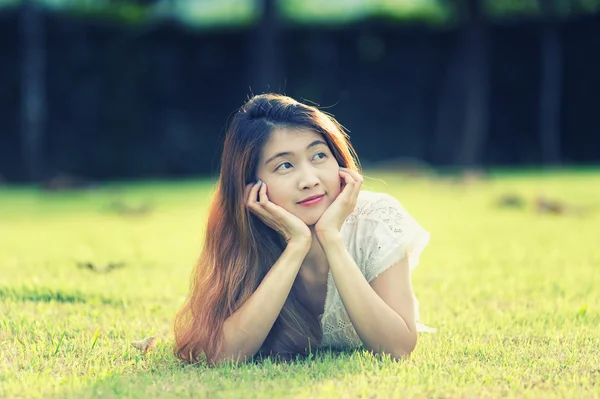 Asie krásná mladá žena leží na zelené trávě — Stock fotografie