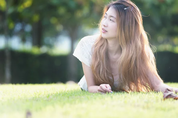 Asie belle jeune femme couchée sur l'herbe verte — Photo