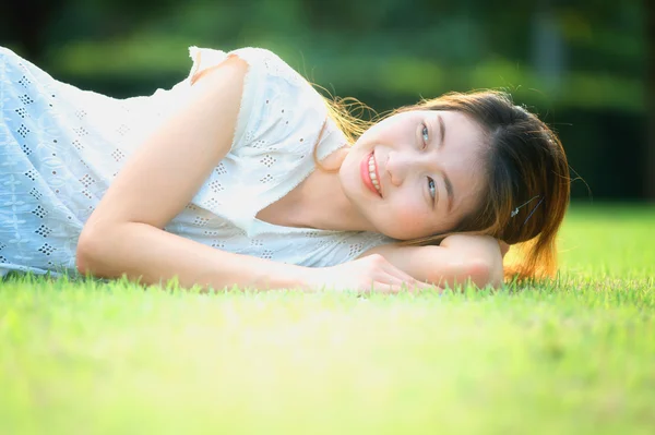 Ásia bela jovem deitado na grama verde — Fotografia de Stock