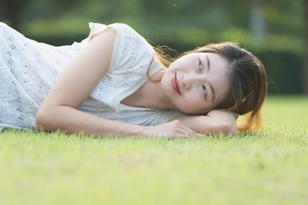 Красивая молодая женщина, лежащая на зеленой траве — стоковое фото