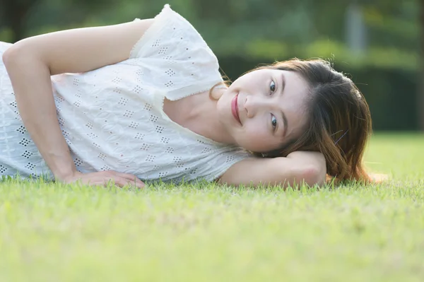 Asia bella giovane donna sdraiata su erba verde — Foto Stock