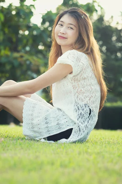 Азія красива молода жінка розслабляється і сидить на зеленій траві — стокове фото
