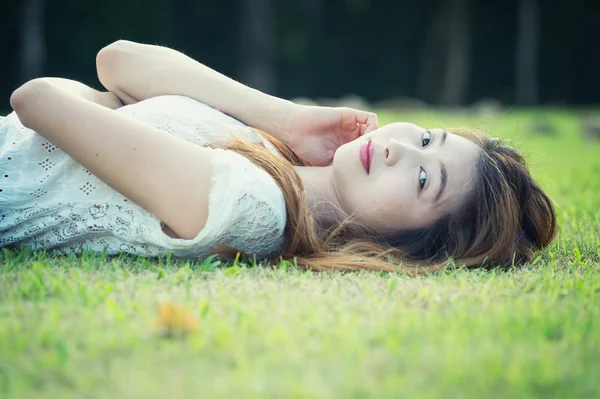 Asia beautiful young woman lying on green grass — Stock Photo, Image