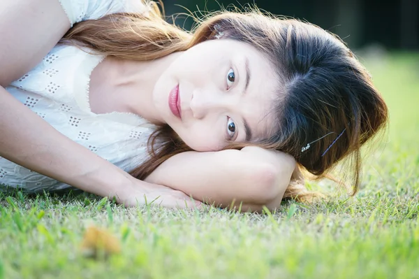 Красивая молодая женщина, лежащая на зеленой траве — стоковое фото