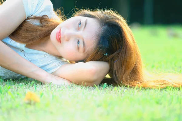 Asia beautiful young woman lying on green grass — Stock Photo, Image