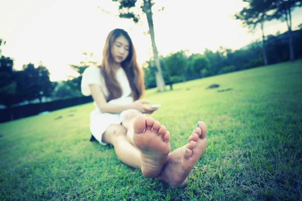 Asiatische Frauen sitzen mit Handy auf Gras — Stockfoto