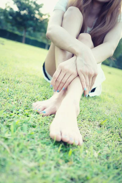 Asiatique détendue jeune femme avec pieds nus assis sur l'herbe — Photo